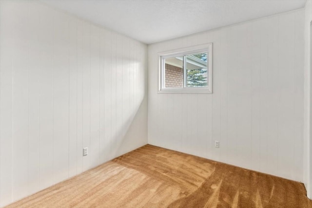 carpeted spare room with wood walls