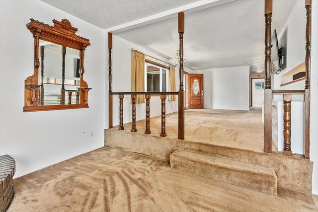 stairway featuring carpet flooring and a textured ceiling