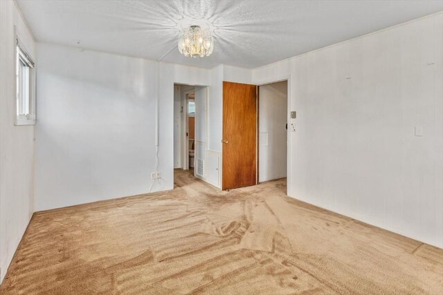 spare room featuring light carpet and an inviting chandelier