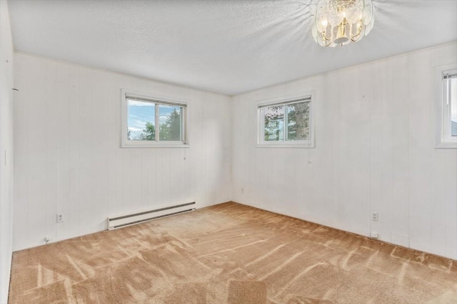 unfurnished room featuring carpet floors, an inviting chandelier, a healthy amount of sunlight, and a baseboard heating unit