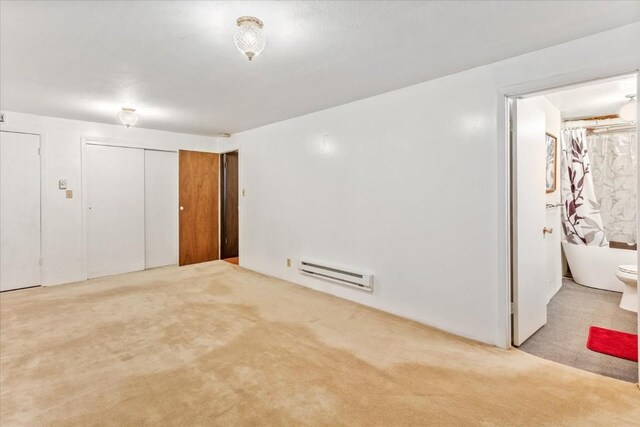 interior space featuring ensuite bath, light carpet, and a baseboard heating unit