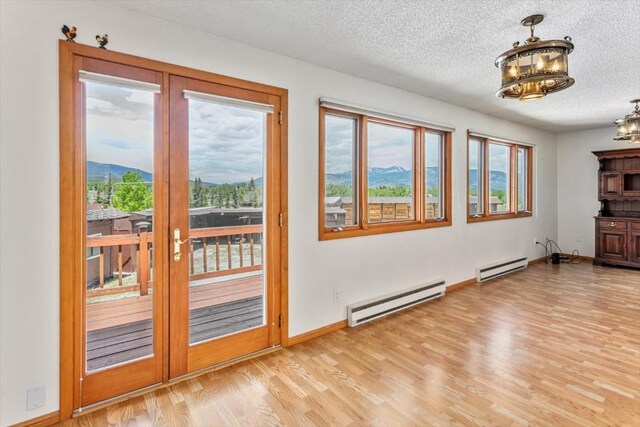 doorway featuring baseboard heating, a mountain view, light hardwood / wood-style flooring, and a notable chandelier