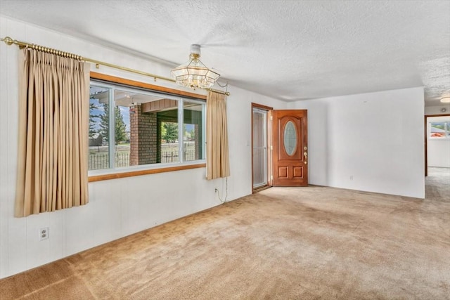 carpeted empty room with a textured ceiling and a chandelier