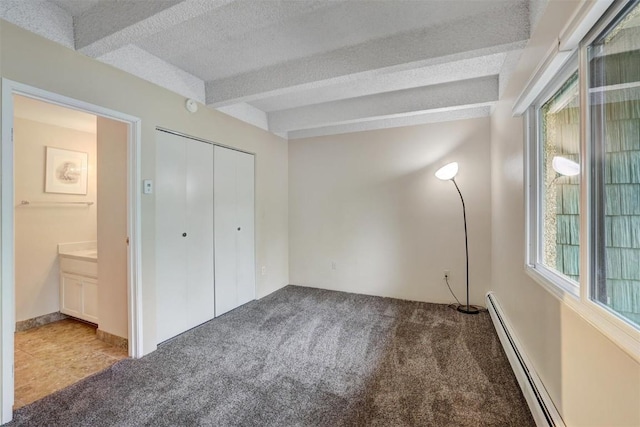 unfurnished bedroom with a baseboard radiator, beamed ceiling, carpet floors, a textured ceiling, and a closet