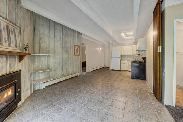 unfurnished living room featuring wood walls, light tile patterned floors, a baseboard radiator, and a textured ceiling