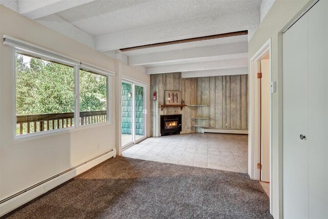 unfurnished living room with wood walls, a textured ceiling, a baseboard radiator, beam ceiling, and light colored carpet