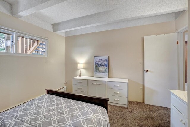 carpeted bedroom with a textured ceiling, beam ceiling, and baseboard heating