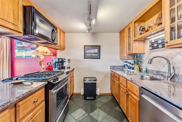 kitchen with rail lighting, light stone countertops, sink, and appliances with stainless steel finishes