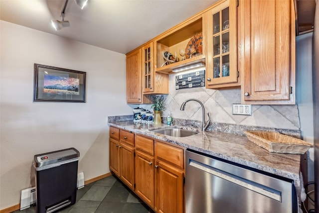 kitchen with dishwasher, sink, light stone counters, dark tile patterned floors, and track lighting