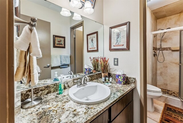 bathroom featuring tile patterned flooring, toilet, an enclosed shower, and vanity