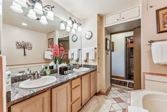 bathroom featuring tile patterned floors, vanity, and a relaxing tiled tub