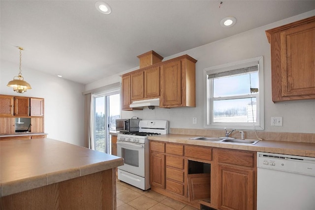 kitchen with a sink, white appliances, under cabinet range hood, and brown cabinetry