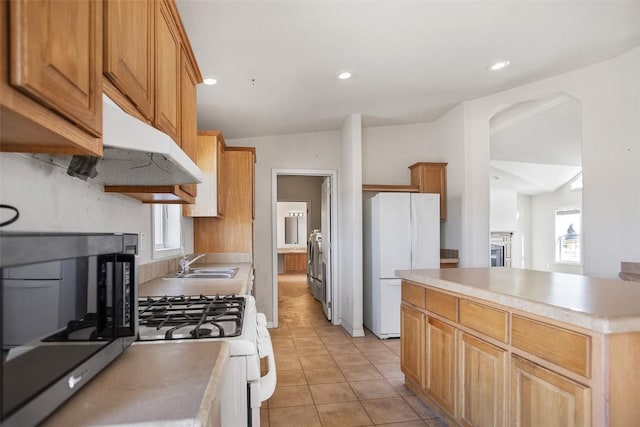 kitchen with white appliances, washer / dryer, light tile patterned flooring, plenty of natural light, and a sink