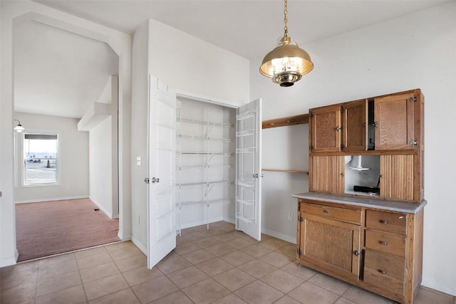 kitchen with brown cabinets, decorative light fixtures, light countertops, light tile patterned floors, and baseboards