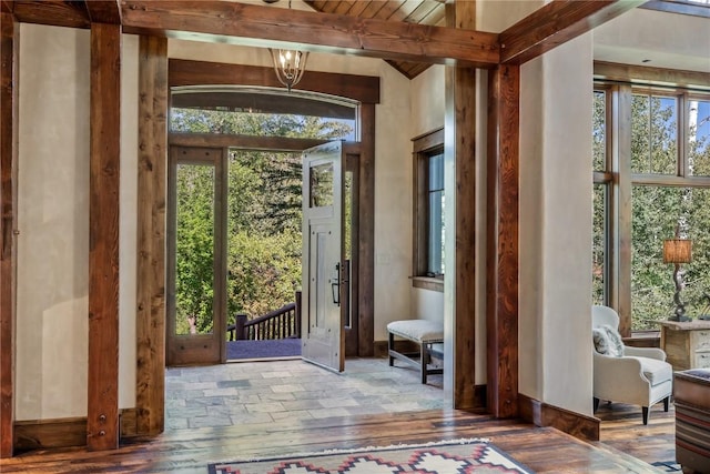 doorway with hardwood / wood-style flooring, a chandelier, and beamed ceiling