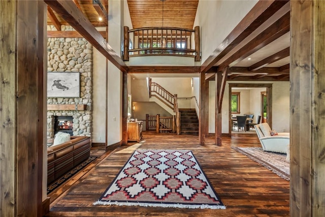 entryway featuring hardwood / wood-style flooring, a high ceiling, a fireplace, a healthy amount of sunlight, and beamed ceiling