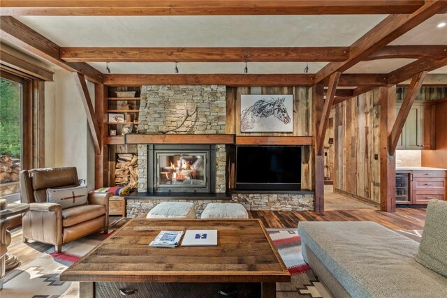 living room with beamed ceiling, beverage cooler, a fireplace, and light hardwood / wood-style floors