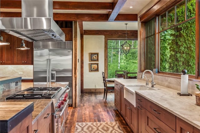 kitchen with pendant lighting, sink, high end appliances, island range hood, and decorative backsplash