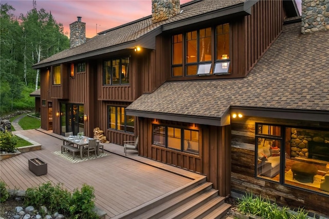 back house at dusk featuring a wooden deck