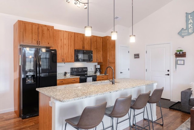 kitchen featuring black appliances, dark hardwood / wood-style floors, a center island with sink, and sink