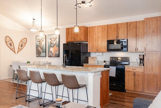 kitchen featuring black appliances, a kitchen island with sink, and dark wood-type flooring