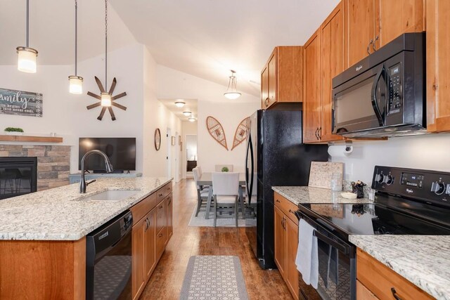 kitchen featuring black appliances, sink, hanging light fixtures, vaulted ceiling, and a fireplace