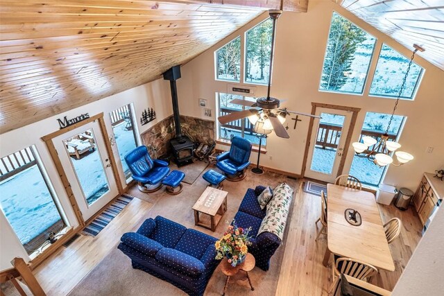 living room with hardwood / wood-style floors, a wood stove, wooden ceiling, high vaulted ceiling, and ceiling fan with notable chandelier