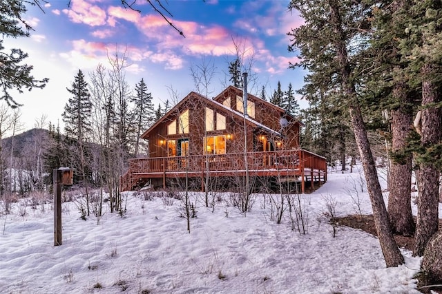 snow covered rear of property with a deck with mountain view