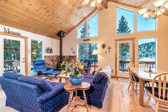 living room with a wood stove, high vaulted ceiling, ceiling fan with notable chandelier, light hardwood / wood-style flooring, and wood ceiling