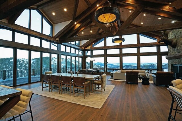 dining space with high vaulted ceiling, wooden ceiling, a mountain view, dark hardwood / wood-style floors, and a stone fireplace