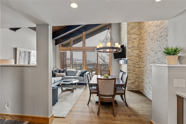 dining area featuring a notable chandelier, wood ceiling, light hardwood / wood-style flooring, and vaulted ceiling with beams