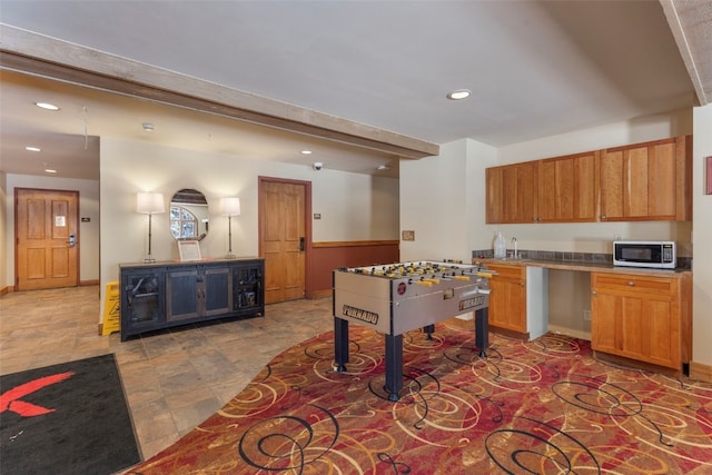 playroom with baseboards, beamed ceiling, stone finish floor, and recessed lighting