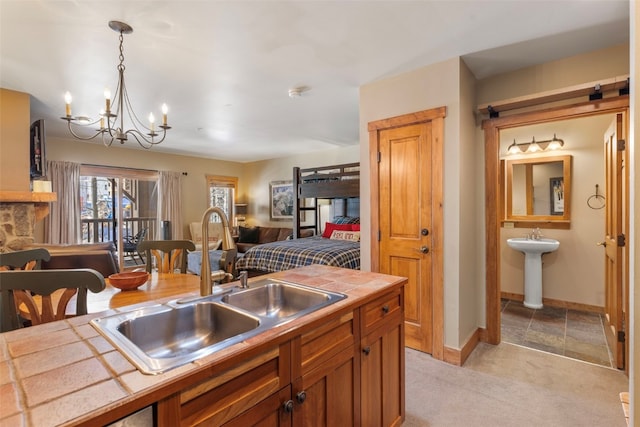 kitchen featuring hanging light fixtures, brown cabinetry, a sink, and tile counters