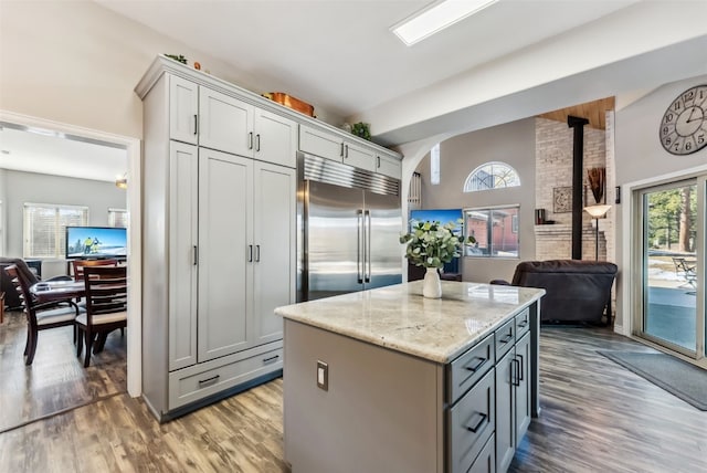 kitchen with a wood stove, plenty of natural light, a center island, and built in fridge