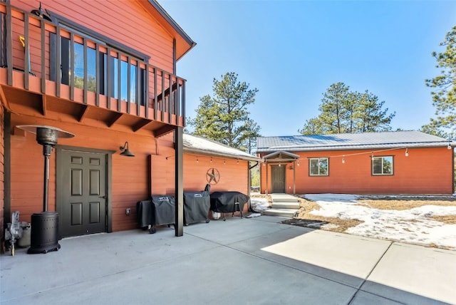 rear view of house featuring metal roof, a patio, and a balcony