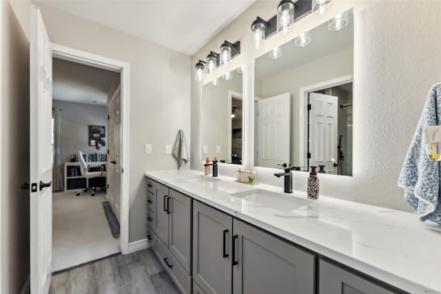 full bathroom with ensuite bathroom, double vanity, wood finished floors, and a sink