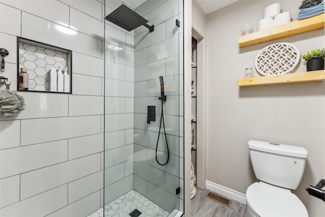 bathroom featuring a stall shower, baseboards, visible vents, toilet, and wood finished floors