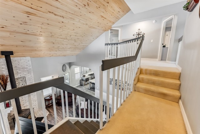 stairs with vaulted ceiling, wooden ceiling, a wood stove, and baseboards