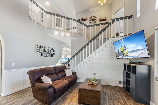 living area featuring high vaulted ceiling, arched walkways, visible vents, and wood finished floors