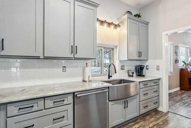 kitchen featuring dark wood-style flooring, a sink, gray cabinets, dishwasher, and tasteful backsplash