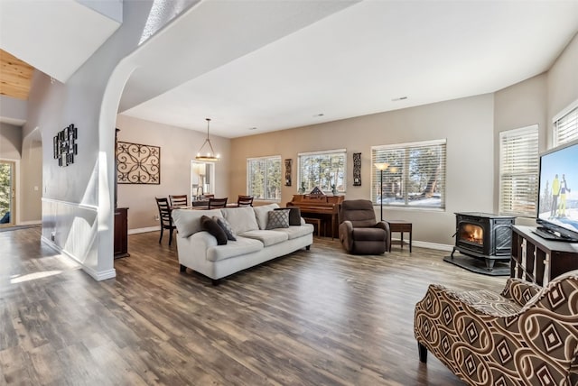 living area with arched walkways, wood finished floors, a wood stove, and baseboards