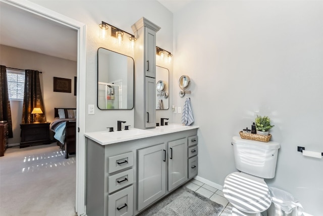 bathroom featuring double vanity, baseboards, ensuite bathroom, tile patterned flooring, and a sink