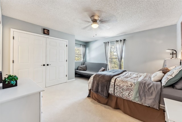 bedroom featuring light carpet, ceiling fan, a closet, and a textured ceiling