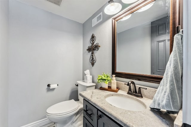 half bath with baseboards, visible vents, vanity, and toilet