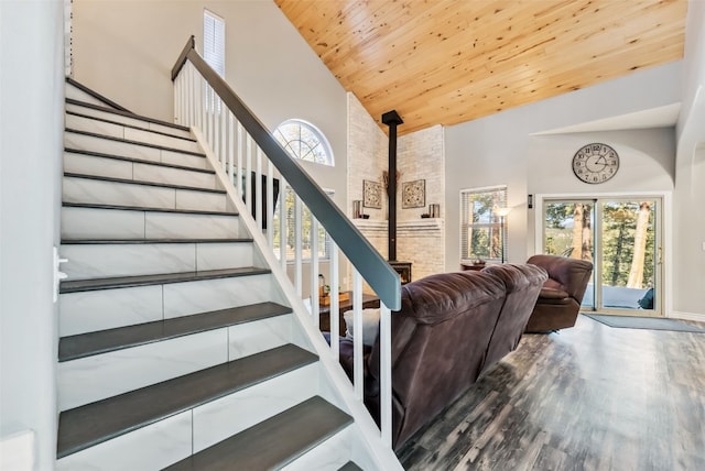 stairs featuring high vaulted ceiling, wooden ceiling, and wood finished floors