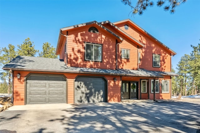 view of front of house with a garage, driveway, and a shingled roof