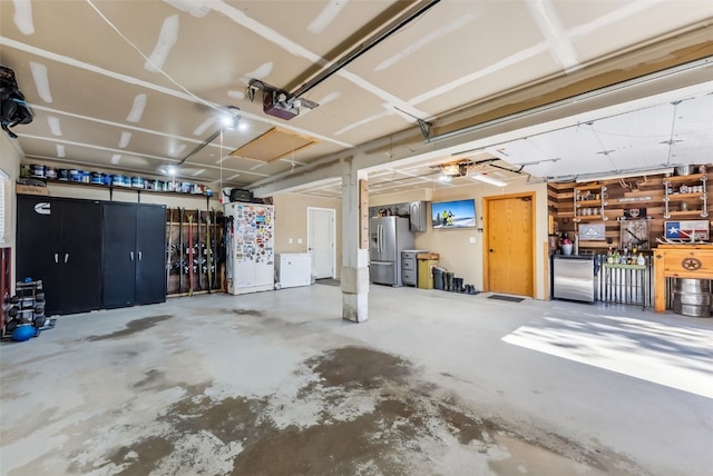 garage with a garage door opener, stainless steel fridge, and stainless steel refrigerator with ice dispenser