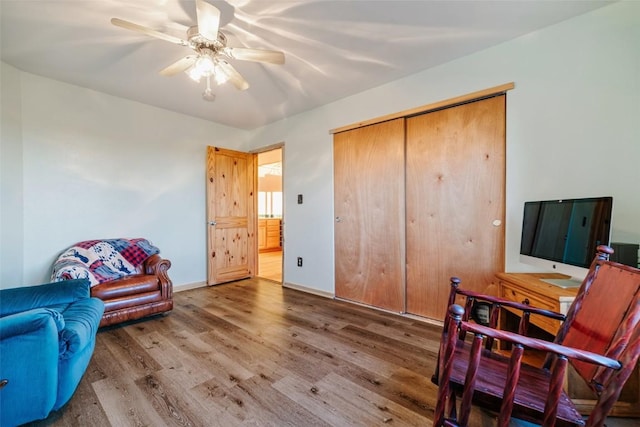 sitting room with ceiling fan and wood-type flooring