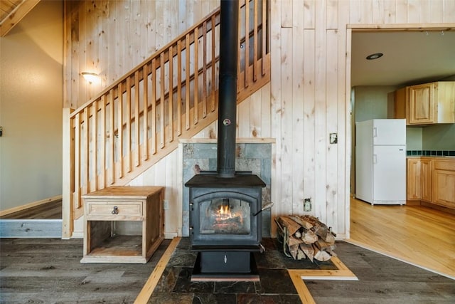 details with wood-type flooring, white fridge, and a wood stove