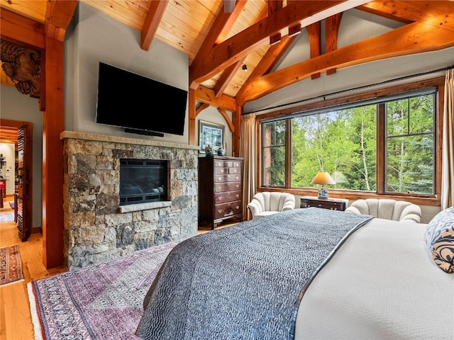 bedroom with vaulted ceiling with beams, hardwood / wood-style floors, and a fireplace